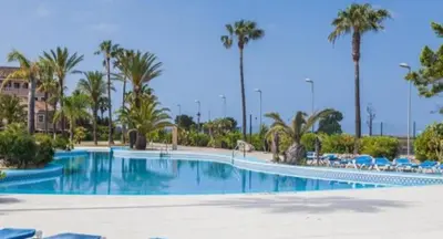 a large swimming pool with palm trees and chairs at Bungalow Bahia Sur 33 in San Fernando