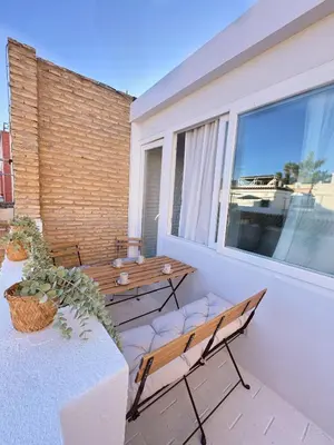 a balcony with two benches and a table and a window at Sibs Sanlucar - casita playa - coqueto vistas in Sanlúcar de Barrameda