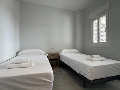 two twin beds in a room with a window at Apartoyou Nuevo Puerto Sherry in El Puerto de Santa María