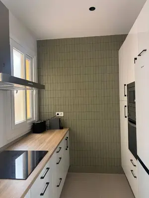 a kitchen with white cabinets and a green tiled wall at Casa Keito, Playa y Patio in Cádiz