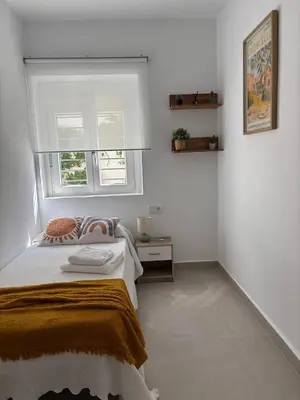 a white bedroom with a bed and a window at Casa Keito, Playa y Patio in Cádiz