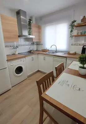a kitchen with a table and a sink and a washing machine at Apartamento Sotavento - 2 dormitorios in Chipiona