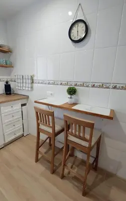a kitchen with a table and two chairs and a clock at Apartamento Sotavento - 2 dormitorios in Chipiona