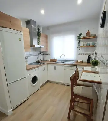 a kitchen with white appliances and a table and chairs at Apartamento Sotavento - 2 dormitorios in Chipiona