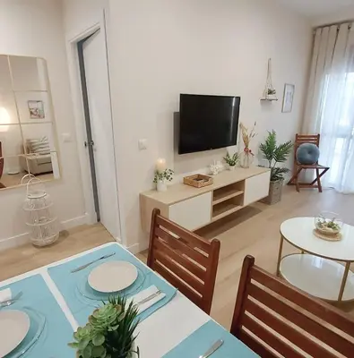 a living room with a television and a table and chairs at Apartamento Sotavento - 2 dormitorios in Chipiona