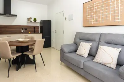 a living room with a couch and a table with chairs at Chiclana Apartamento zona playa in Chiclana de la Frontera