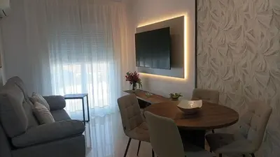 a living room with a table and a tv on a wall at Chiclana Apartamento zona playa in Chiclana de la Frontera