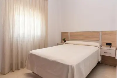 a bedroom with a large white bed and a window at Chiclana Apartamento zona playa in Chiclana de la Frontera