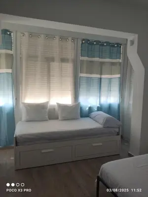 a bedroom with a bed with two windows at Mi Rinconcito in Chipiona
