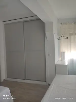 a white bedroom with a sliding glass door at Mi Rinconcito in Chipiona