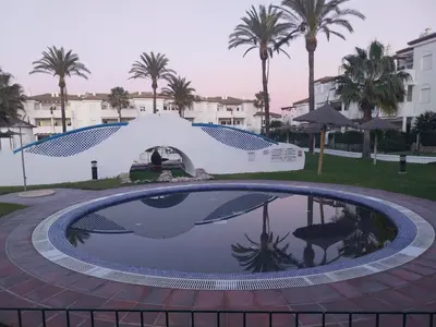a large swimming pool with a pavilion and palm trees at Apartamento Taymar Daniel in Chiclana de la Frontera