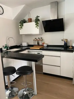 a kitchen with white cabinets and black counter tops at Apartamento Colegueo in Sanlúcar de Barrameda