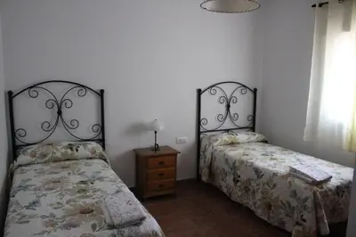 a bedroom with two beds and a night stand and a window at Chalet con piscina privada en Conil in Cádiz