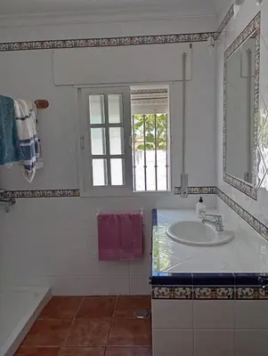 a white bathroom with a sink and a window at Chalet con piscina privada en Conil in Cádiz