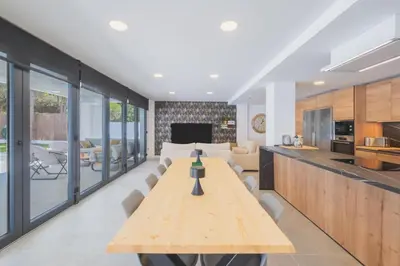 a kitchen and living room with a wooden table at Increíble Villa en campo de golf in Novo Sancti Petri