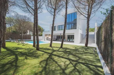 a view of a house with a fence and trees at Increíble Villa en campo de golf in Novo Sancti Petri