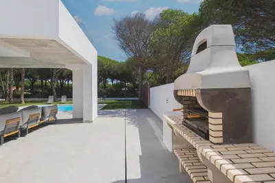 an outdoor patio with a fireplace on a white wall at Increíble Villa en campo de golf in Novo Sancti Petri