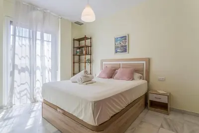 a bedroom with a large bed with pink pillows at Playa de fuentebravía in El Puerto de Santa María