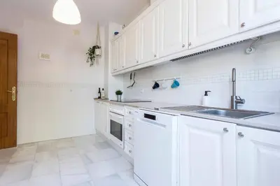 a white kitchen with white cabinets and a sink at Playa de fuentebravía in El Puerto de Santa María