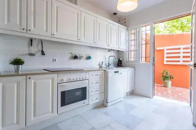 a white kitchen with white cabinets and a window at Playa de fuentebravía in El Puerto de Santa María