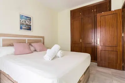 a bedroom with a large white bed with pink pillows at Playa de fuentebravía in El Puerto de Santa María