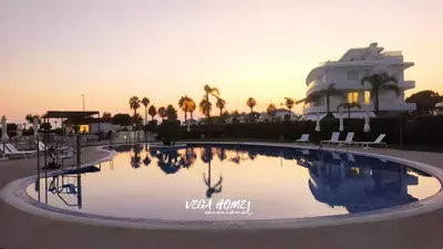 a pool with chairs and a building in the background at Apartamento Eleven View Costa ballena MOON BLACK in Costa Ballena