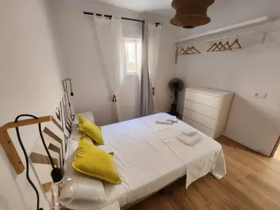 a bedroom with a white bed with yellow pillows at Casa Las Piletas in Sanlúcar de Barrameda
