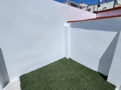 a white wall with a patch of green grass at Casa Las Piletas in Sanlúcar de Barrameda