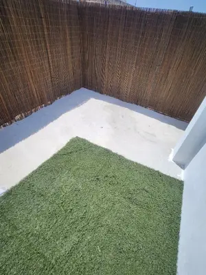 a small yard with green grass next to a fence at Casa Las Piletas in Sanlúcar de Barrameda