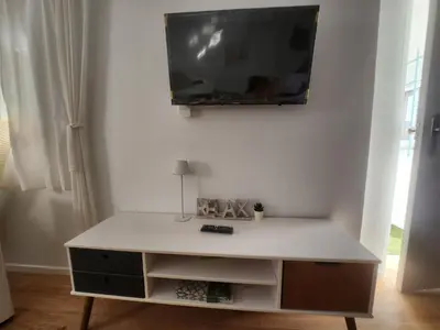 a living room with a tv on a white wall at Casa Las Piletas in Sanlúcar de Barrameda