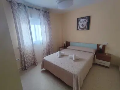 a bedroom with a bed and a picture of a man at Apartamento Plaza Alta in Sanlúcar de Barrameda