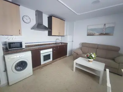 a kitchen and living room with a couch and a table at Apartamento Plaza Alta in Sanlúcar de Barrameda