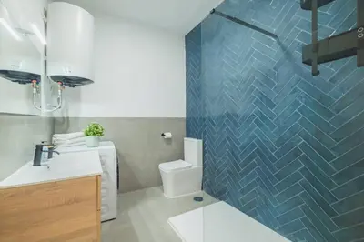 a bathroom with a toilet and a blue tiled wall at Cadizz- Andalusian Green Palace - ideal familias centro del Puerto Santa María in El Puerto de Santa María