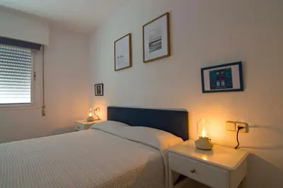 a bedroom with a bed and two tables with lights at Pinar de la Almadraba, Apartamentos Living Sur in Rota