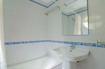 a white bathroom with a sink and a mirror at Pinar de la Almadraba, Apartamentos Living Sur in Rota