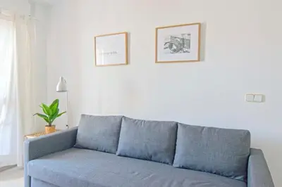 a blue couch in a living room with two pictures on the wall at Pinar de la Almadraba, Apartamentos Living Sur in Rota