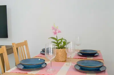 a table with plates and glasses and a plant on it at Pinar de la Almadraba, Apartamentos Living Sur in Rota