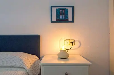 a lamp on a night stand next to a bed at Pinar de la Almadraba, Apartamentos Living Sur in Rota
