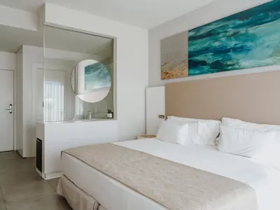 a white bedroom with a bed and a mirror at Grupotel Conil Playa - Adults Only Recommended in Conil de la Frontera