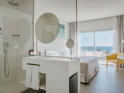 a bathroom with a sink and a mirror and a bed at Grupotel Conil Playa - Adults Only Recommended in Conil de la Frontera