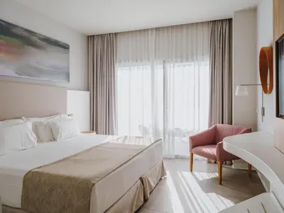 a hotel room with a bed and a chair at Grupotel Conil Playa - Adults Only Recommended in Conil de la Frontera