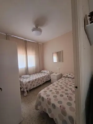 a small bedroom with two beds and a window at Arena y Sol in Chipiona