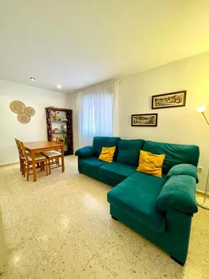 a living room with a green couch and a table at El Viñero, Apartamento con garaje in Cádiz