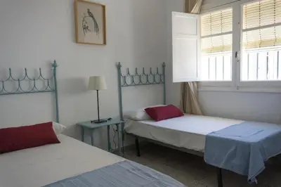 a bedroom with two beds and a window and a lamp at Magnifico alojamiento a 14 metros de la playa con magnificas vistas in Chipiona