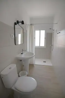 a white bathroom with a toilet and a sink at Magnifico alojamiento a 14 metros de la playa con magnificas vistas in Chipiona