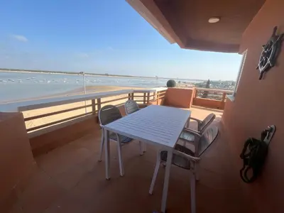a table and chairs on a balcony with a view of the ocean at Mirador de Sanlucar 2 in Sanlúcar de Barrameda