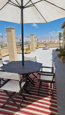a picnic table with two chairs and an umbrella on a rug at Ático con espléndida terraza in Cádiz