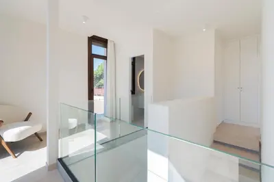 a glass staircase in a white room with a chair at Casa Aura in Novo Sancti Petri
