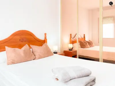 a bedroom with a white bed and a mirror at Apartamento La Caleta Grupo AC Gestion in Cádiz