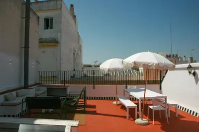 two white umbrellas on a balcony with tables and chairs at Caleta Club - Rooftop Villa, Cádiz in Cádiz